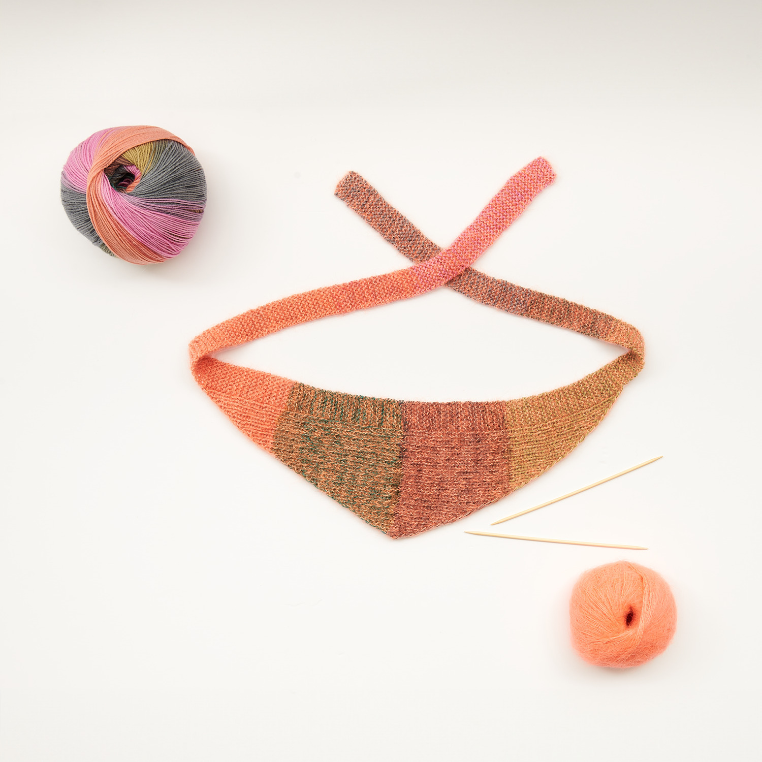 Mini Tücher Special: Dreieckstuch in Orange- und Brauntönen mit Stricknadeln und Garnknäuel.