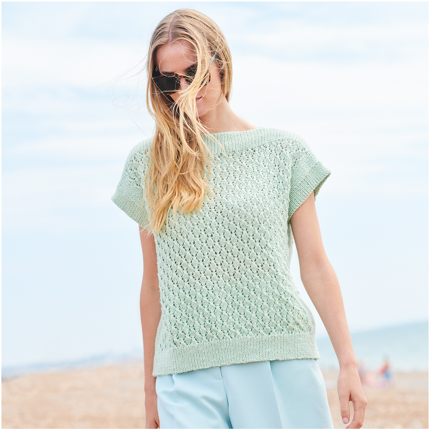Strickset Top Modell 27 aus Lovewool Nr. 18: Frau am Strand in mintgrünem, kurzärmligem Stricktop.