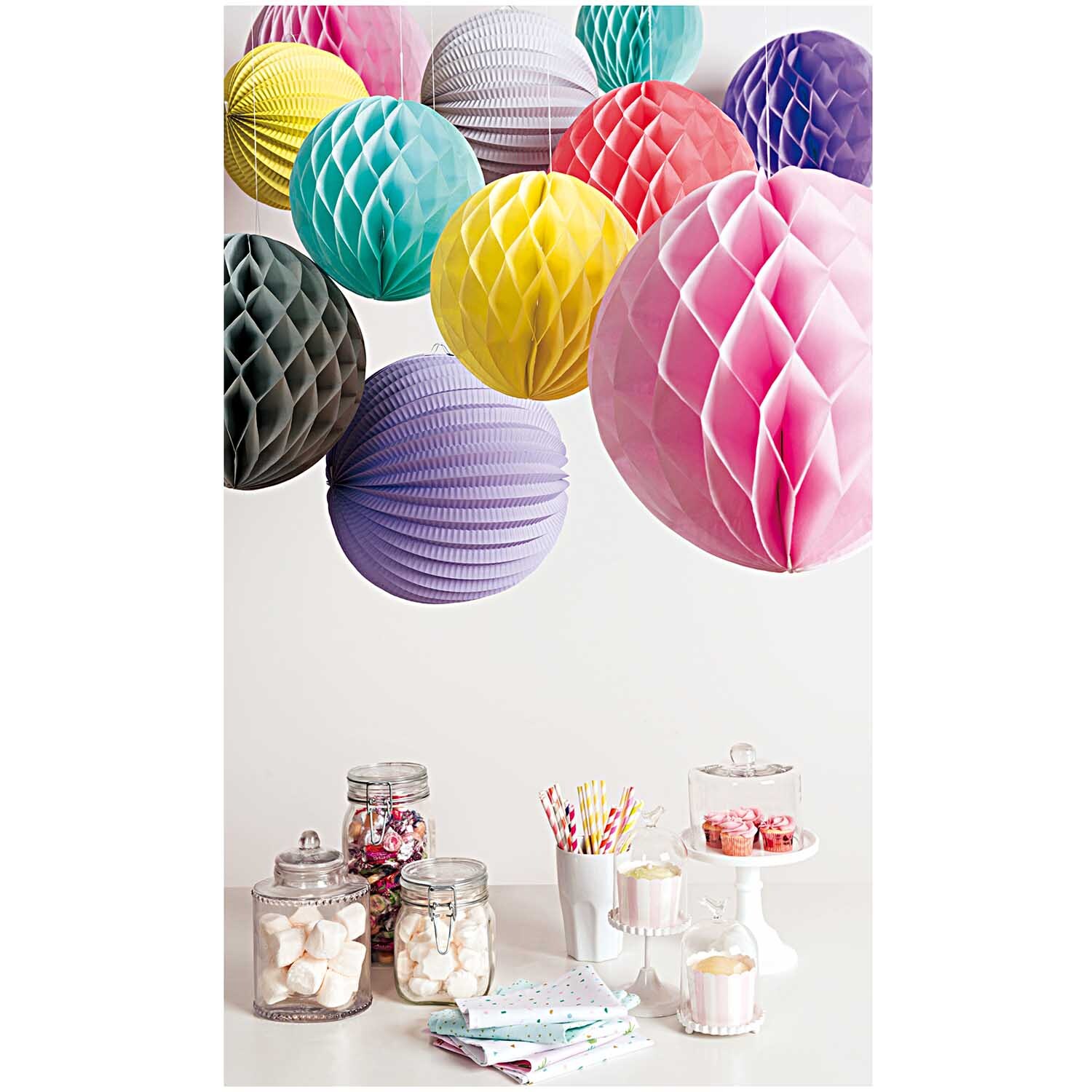 Lampions pastell 3 Stück: Bunte Papierlampions von Rico Design schweben über einem Tisch mit Süßigkeiten und Dekorationen.