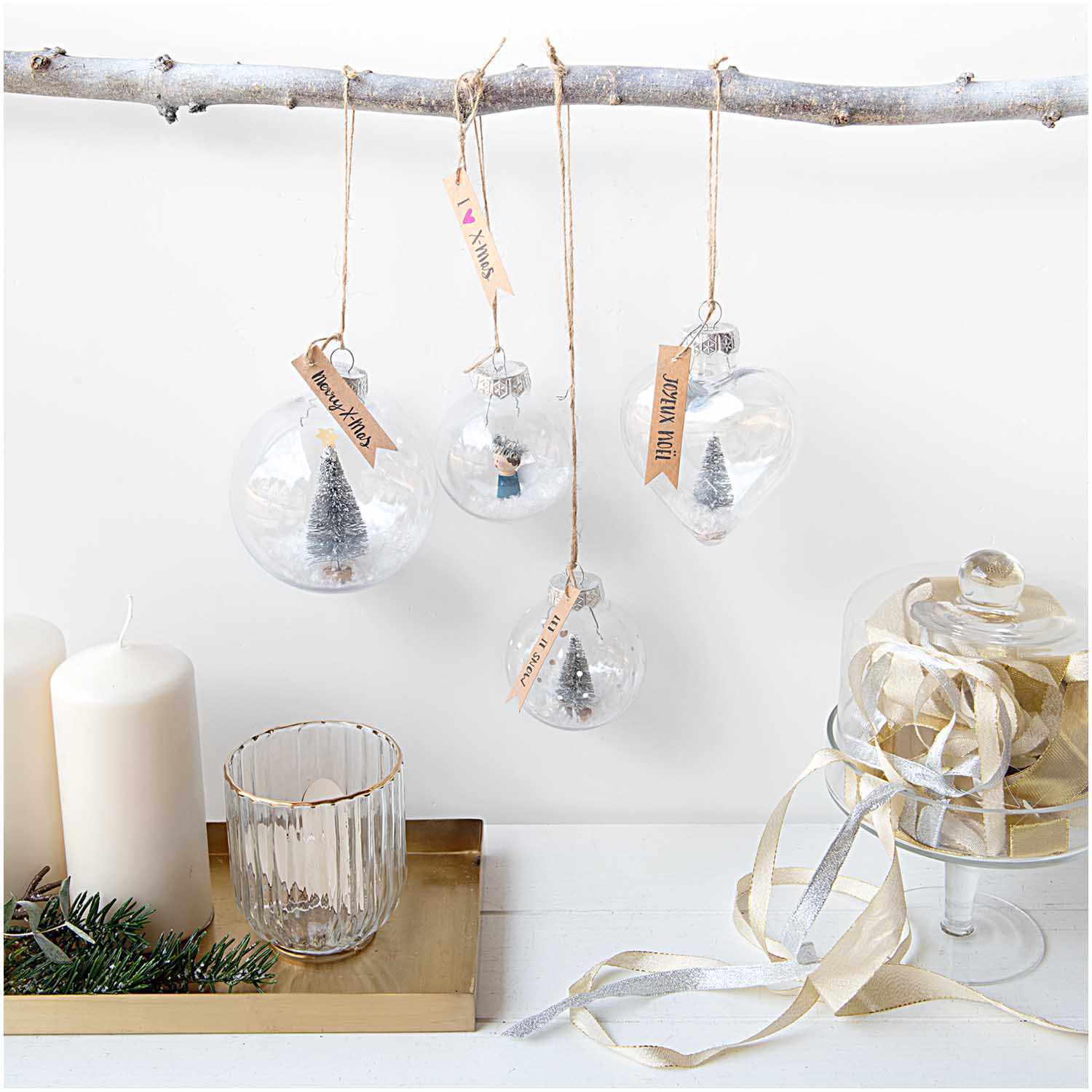 Weihnachtskugel aus Kunststoff 10cm mit Miniaturbäumen, hängend an einem Ast, von Rico Design.
