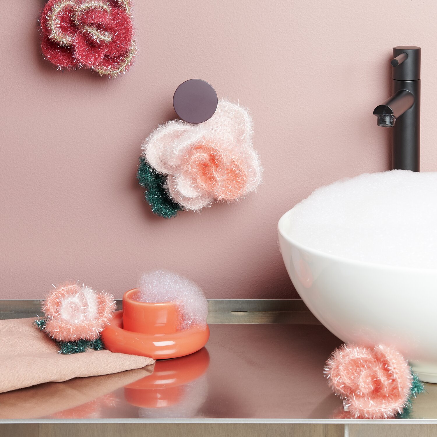 Häkelset Creative Bubble Rose Romantic: Flauschige Rosen in Pastelltönen neben Waschbecken.