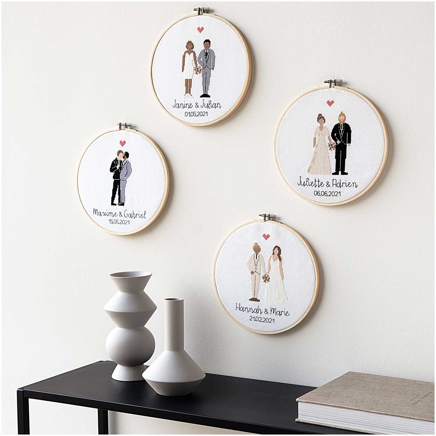 Figurico Stickpackung Wedding Ø 20cm zeigt vier bestickte Hochzeitsmotive in Holzrahmen an einer Wand.