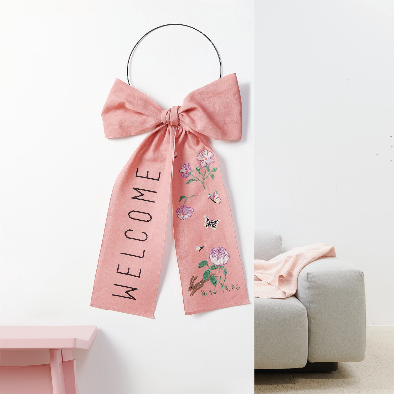 Stickpackung Schleife Welcome: Rosa Schleife mit floralen Motiven und "Welcome"-Schriftzug, 38x80cm.