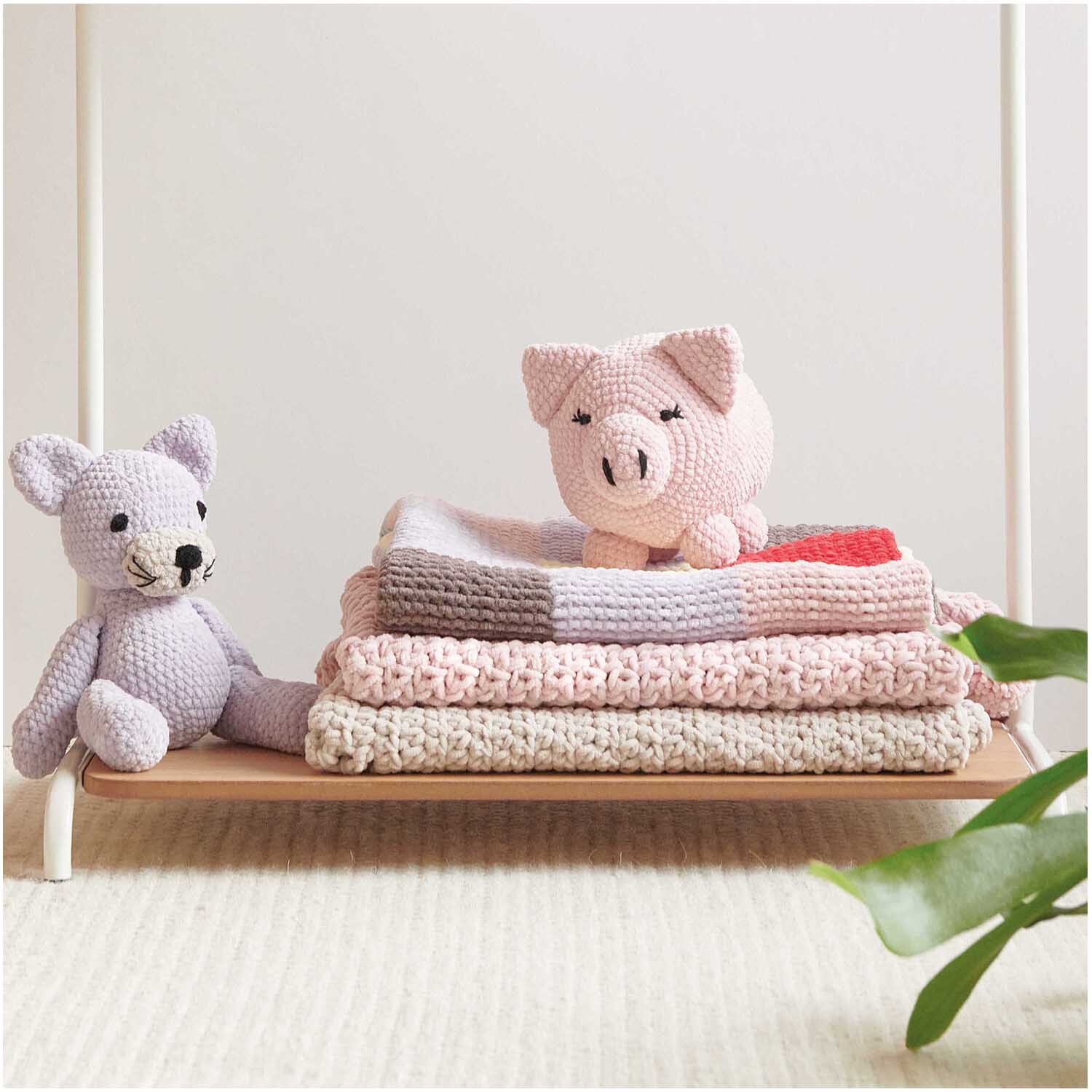 Creative Chenillove: Handgefertigte rosa Kuscheltiere und Decken von Rico Design auf einem Holzregal.