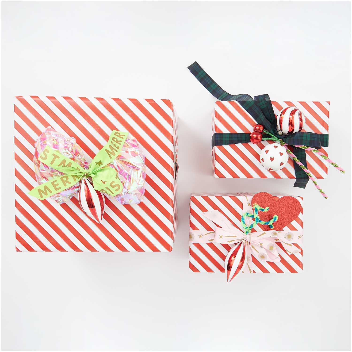 Paper Poetry Geschenkpapier mit rot-weißen Streifen, dekoriert mit Schleifen und weihnachtlichen Motiven. Ideal für festliche Anlässe.