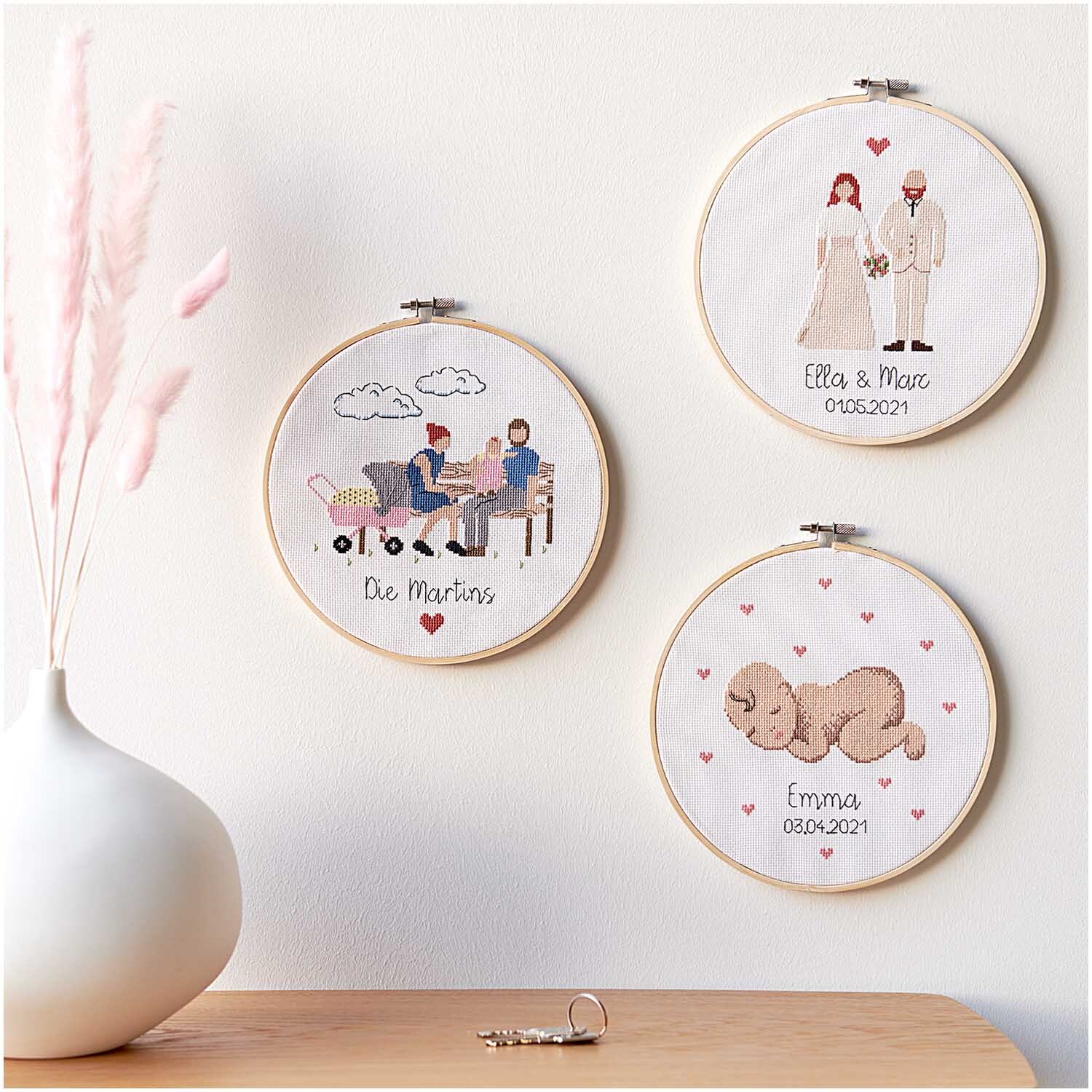 Figurico Stickpackung Wedding Ø 20cm zeigt drei bestickte Rahmen mit Hochzeits- und Familienmotiven an einer Wand.