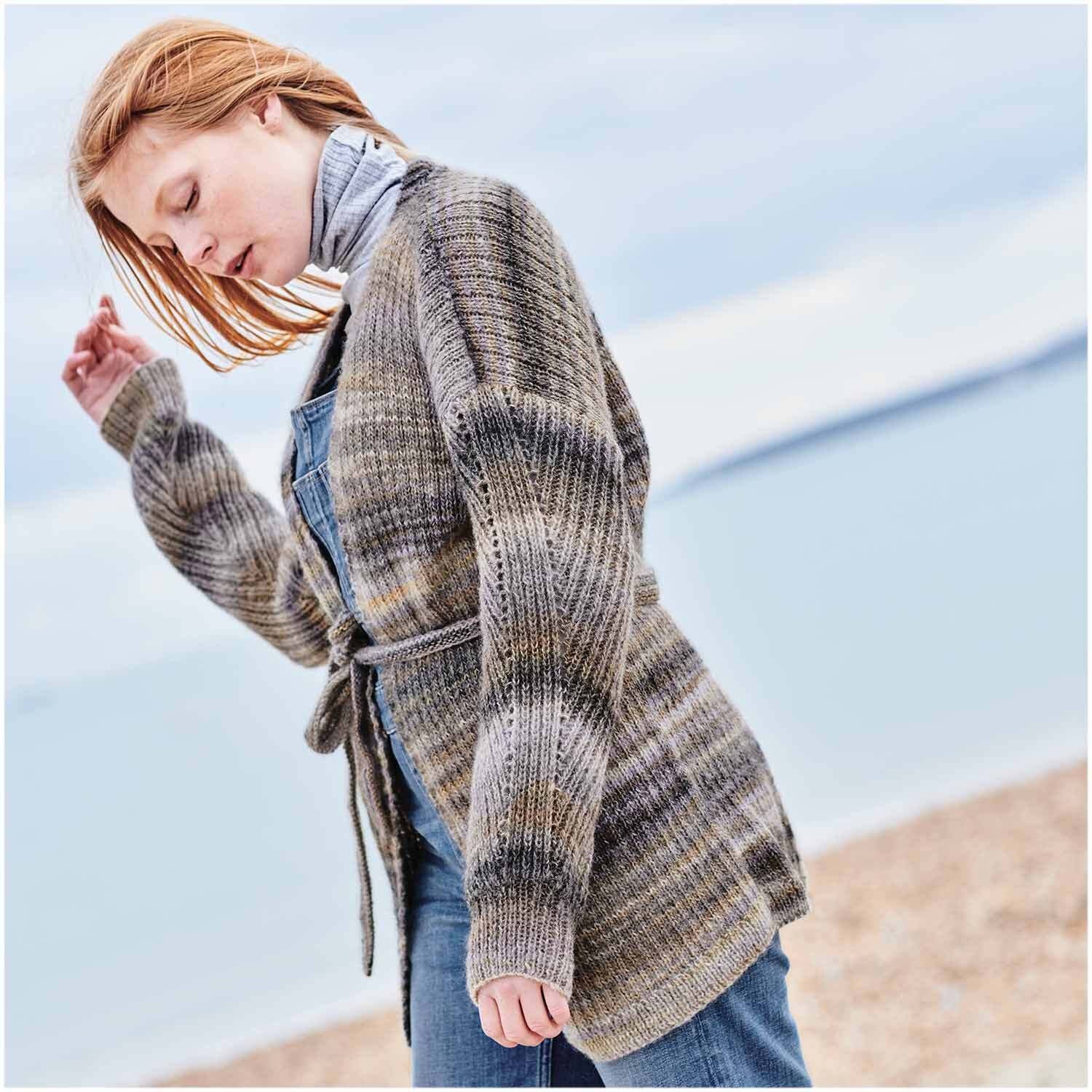 Creative Melange Garzato aran Wonderball: Frau am Strand in gestrickter, melierter Strickjacke von Rico Design.