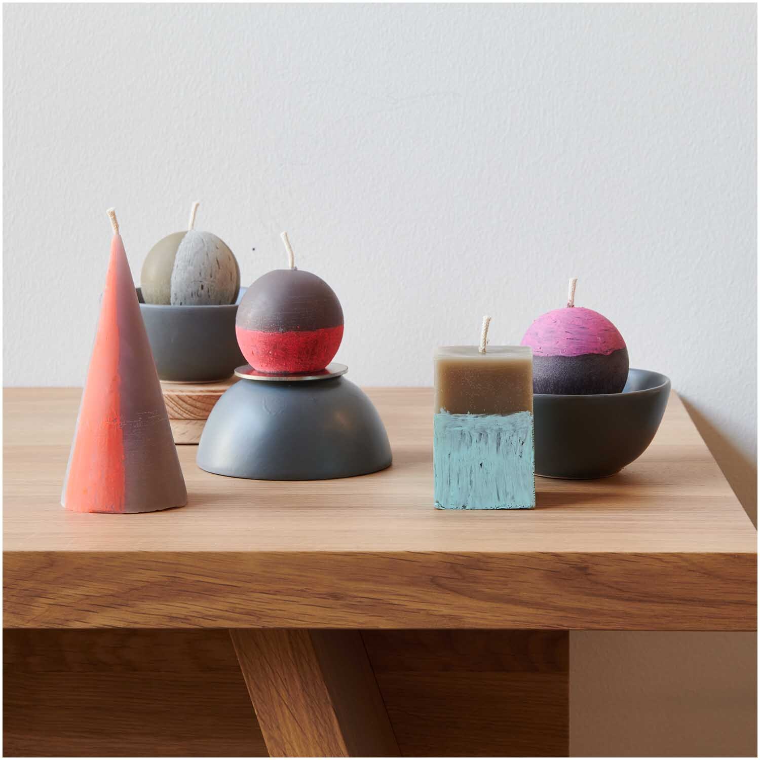 Kerzengießform Kegel 75x75x150mm von Rico Design auf einem Tisch mit bunten Kerzen in verschiedenen Formen und Farben.