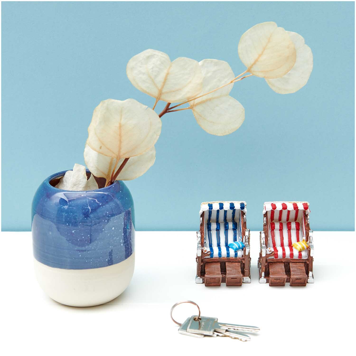 Deko-Strandkorb blau-weiß 5x6,5cm von Rico Design neben einem blauen Keramiktopf mit Trockenblumen.