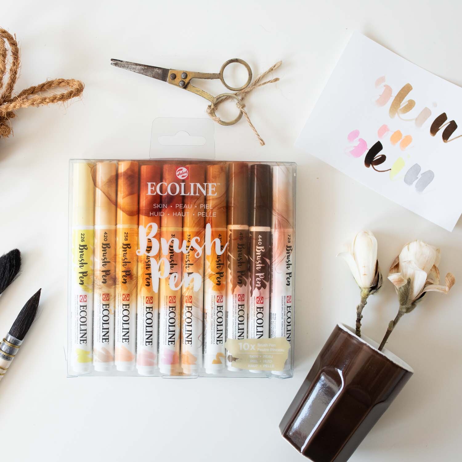 Brush Pen Set 10 Stück von ECOLINE in Hauttönen, präsentiert auf einem Tisch mit Blumen und Tasse. Ideal für kreative Projekte.