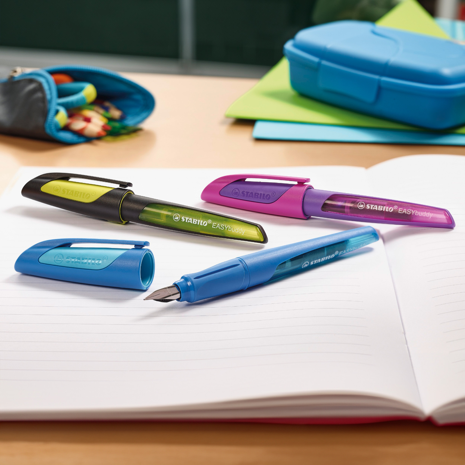 Easybuddy Patronenfüller für Linkshänder auf einem Schreibtisch mit bunten Stiften und Etui.