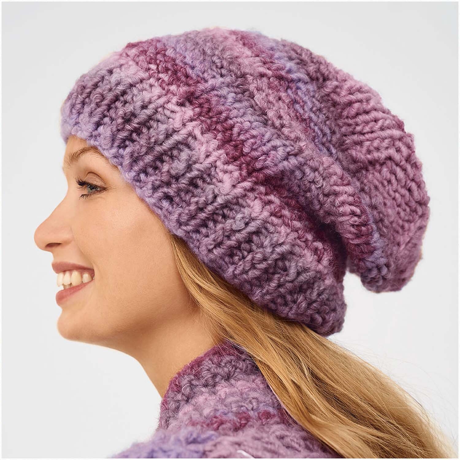 Super Big Color: Frau trägt eine gestrickte Mütze in Lila-Tönen, passend zu ihrem Schal. Ideal für kalte Tage.