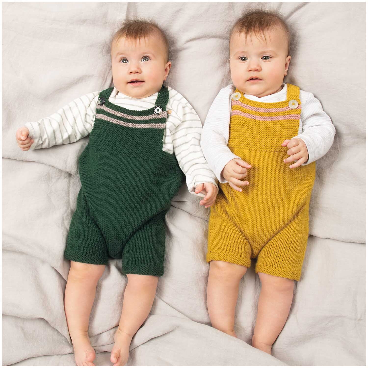 Rico Baby Classic dk: Zwei Babys in gestrickten Overalls, einer in Senf, der andere in Grün, auf einer Decke liegend.