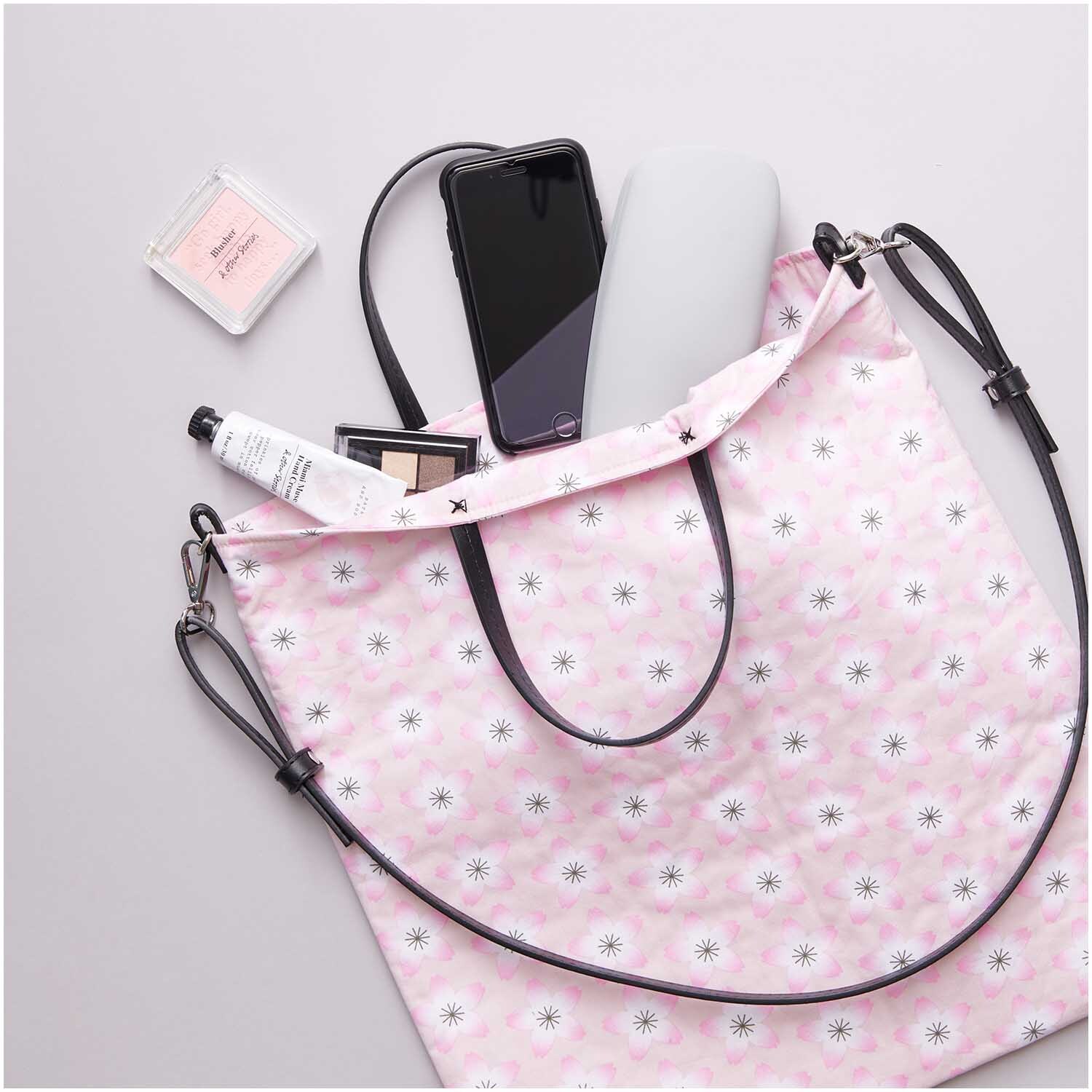 Kunstleder Taschengriffe kurz schwarz von Rico Design, befestigt an einer rosa gemusterten Tasche mit Alltagsgegenständen.