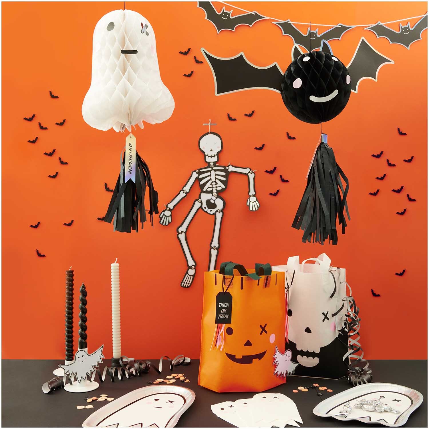 Servietten Gespenst 33x40cm 20 Stück: Halloween-Dekoration mit weißen Gespenst-Servietten, Skelett und Fledermaus vor orangefarbener Wand.