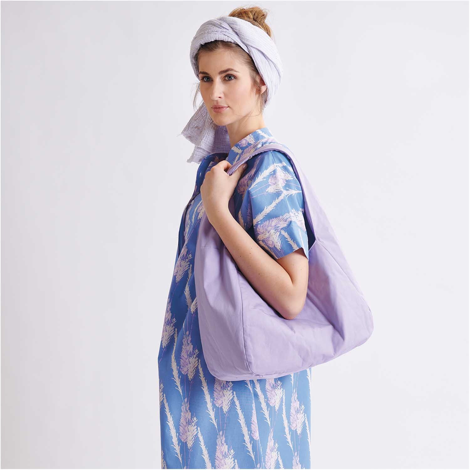 Meterware Krinkelmusselin hellgrau Hot Foil: Frau in blauem Kleid mit lila Tasche und Kopftuch. Stoff von Rico Design.