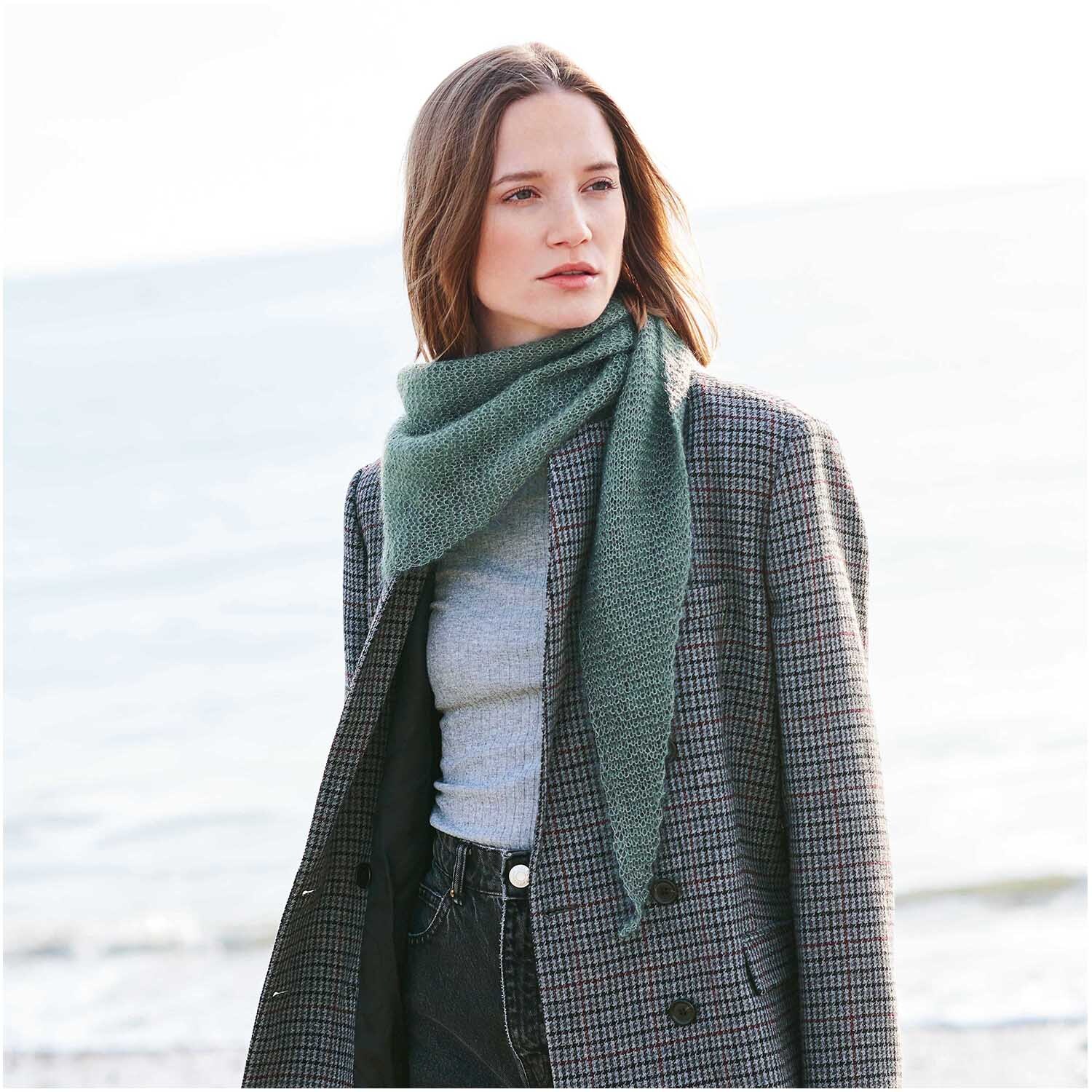 Strickset Dreieckstuch Modell 15 aus Accessoire Special: Frau am Strand mit grünem Schal und kariertem Mantel.
