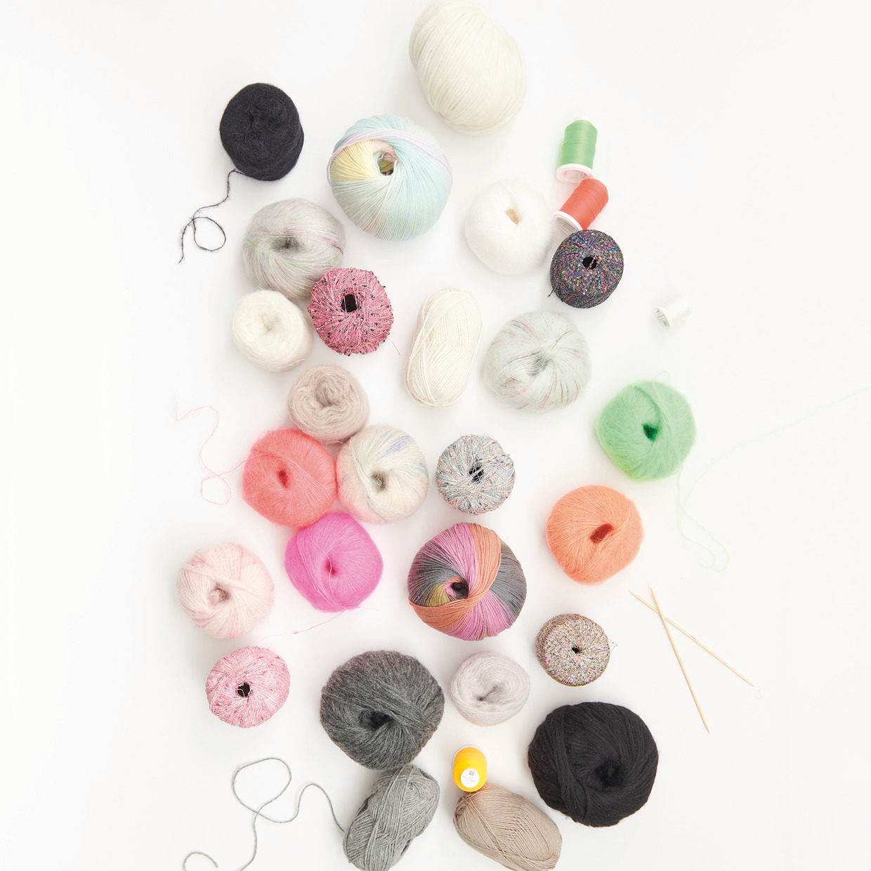 Mini Tücher Special: Bunte Garnknäuel und Strickzubehör auf weißem Hintergrund, ideal für kreative Projekte.