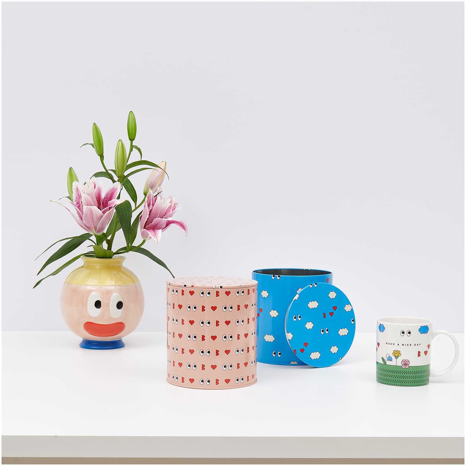 Rico Design x Redfries Keksdose Wolken blau 13,5x15cm neben einer Blumenvase, einer weiteren Dose und einer Tasse auf einem Tisch.