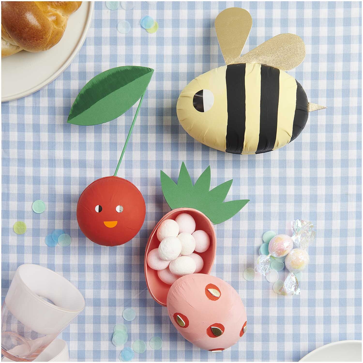Pappmaché Kugel weiß 8cm von Rico Design auf kariertem Tischtuch mit bunten Dekorationen.