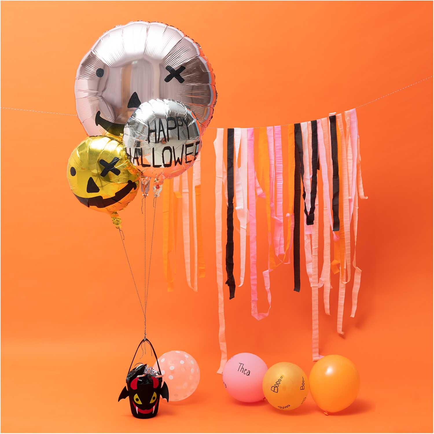Luftballon Mix Halloween 30cm 12 Stück: Bunte Ballons mit Halloween-Motiven vor orangefarbenem Hintergrund.