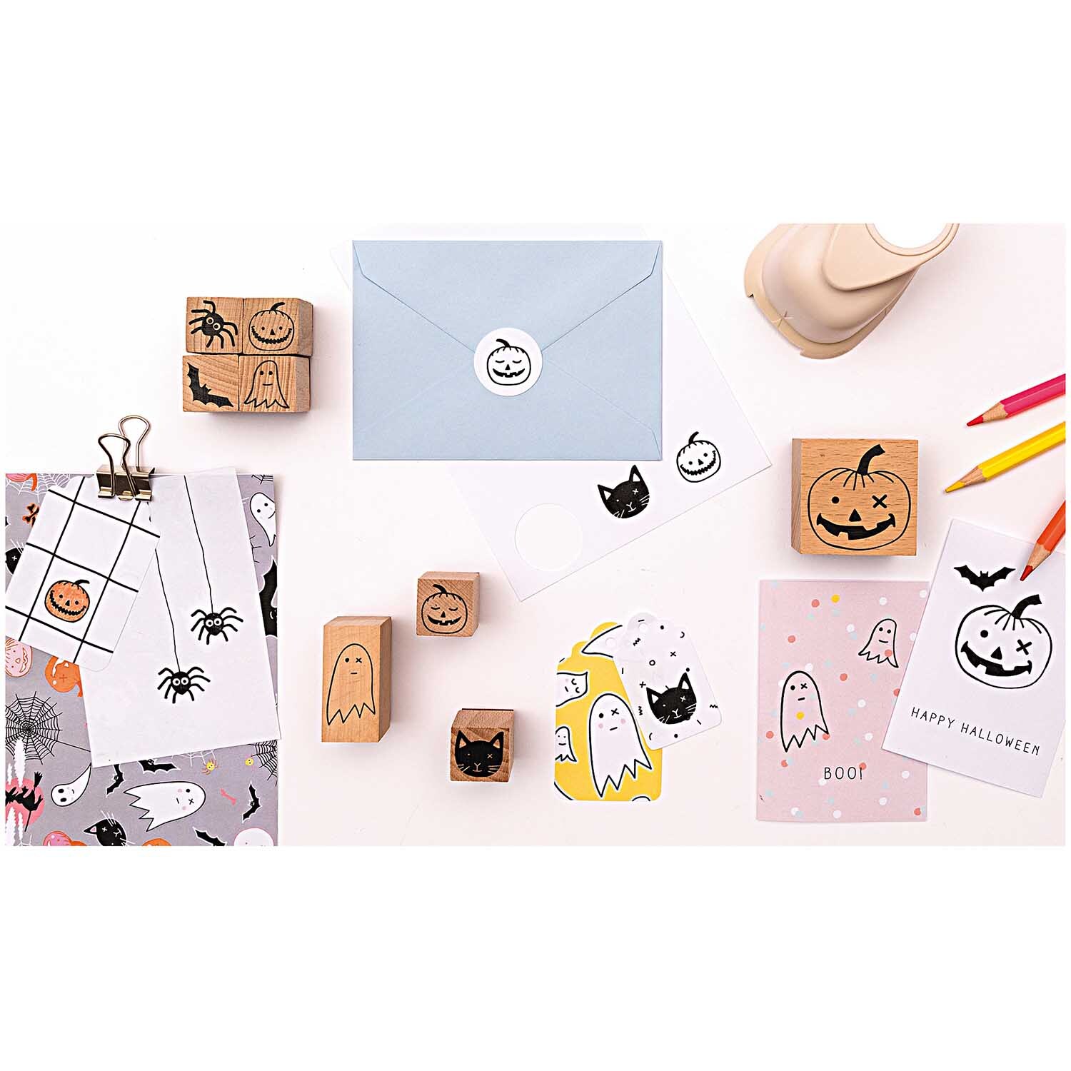 Paper Poetry Foldback Klammern in Gold, umgeben von Halloween-Stempeln, Karten und Umschlägen. Ideal für kreative Bastelprojekte.
