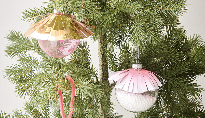 Bastelanleitung Christbaumkugeln mit Neon Details: Zwei bunte Kugeln mit Papierdekor an einem Tannenbaum.