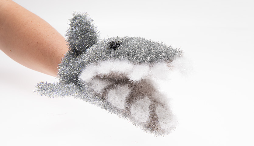 Häkelanleitung Waschhandschuh Hai: Ein grauer, flauschiger Waschhandschuh in Form eines Hais auf einer Hand.