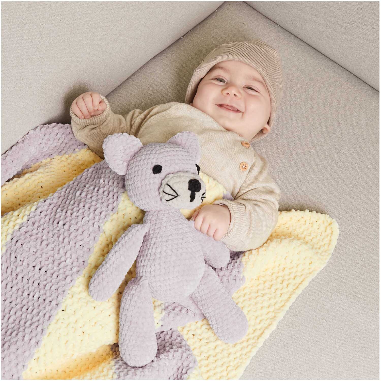 Creative Chenillove: Ein Baby liegt auf einer gestrickten Decke mit einem weichen, gestrickten Teddybär.