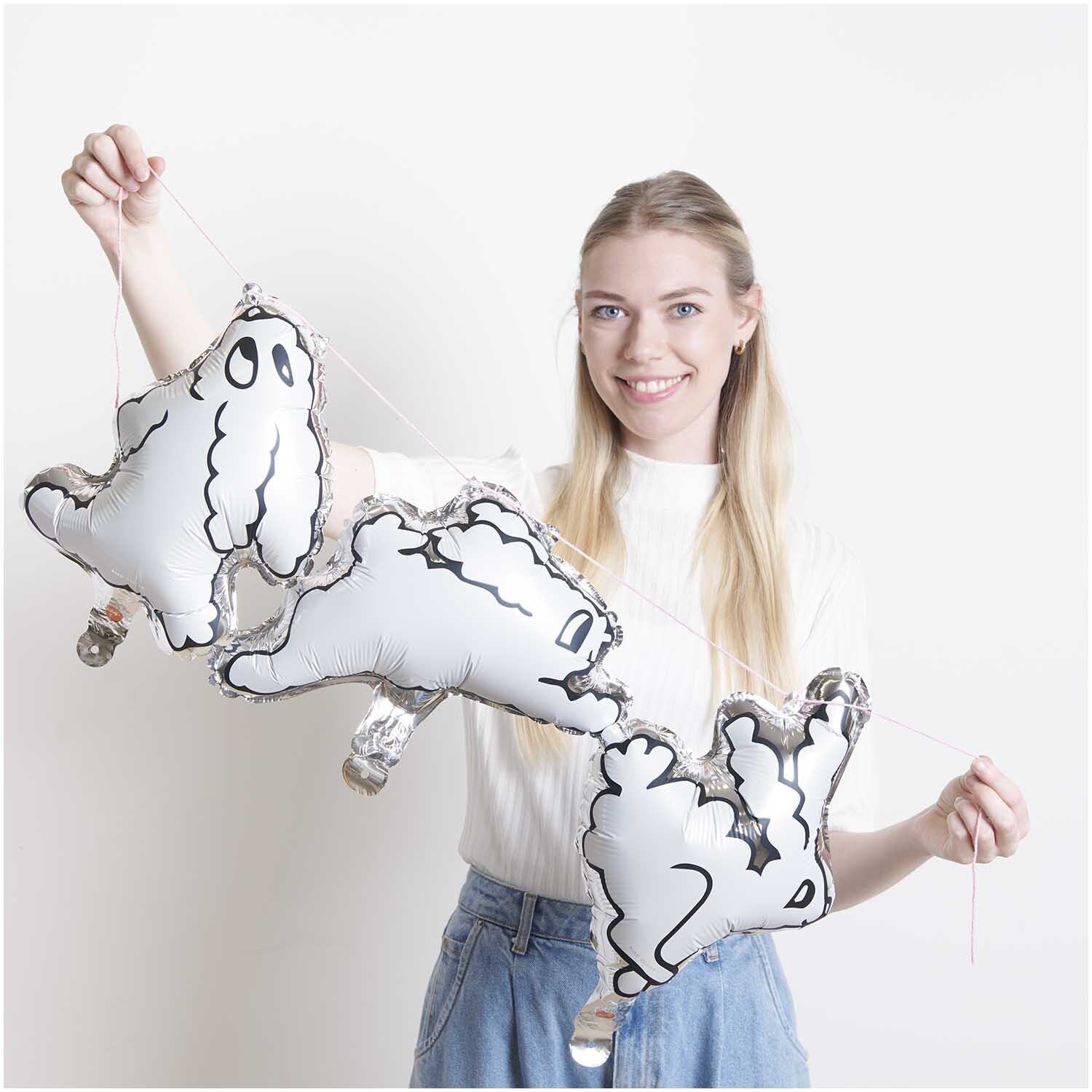 Mini-Folienballon Set Hasen: Frau hält drei weiße Hasenballons von Rico Design vor weißem Hintergrund.