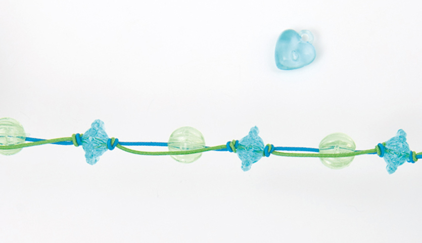 Anleitung DIY Perlenset Beads Armband basteln: Blau-grünes Armband mit Herzperlen auf weißem Hintergrund.