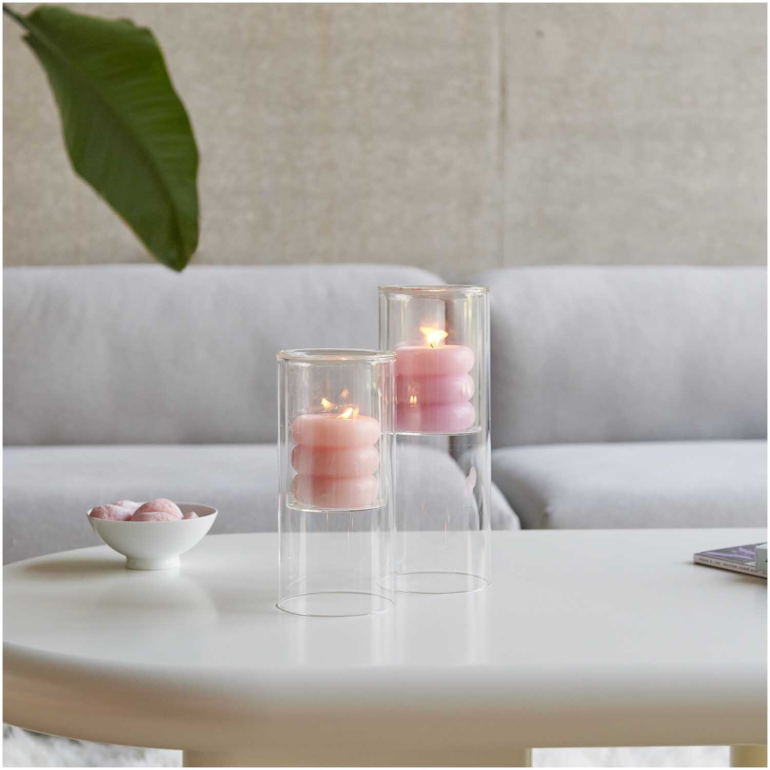 Glas-Windlicht auf einem Tisch mit brennenden Kerzen, dekoriert in einem modernen Wohnzimmer.