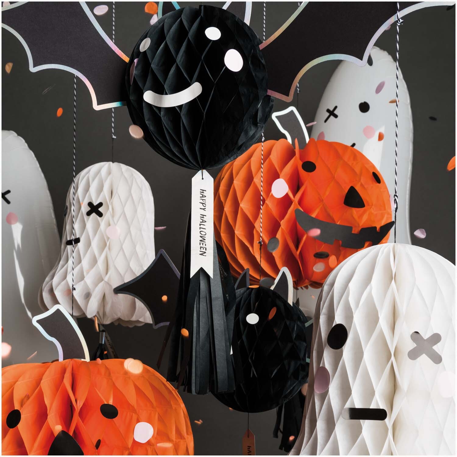 Wabenpapierfigur mit Quaste Fledermaus von Rico Design, umgeben von Halloween-Dekorationen wie Kürbissen und Geistern.