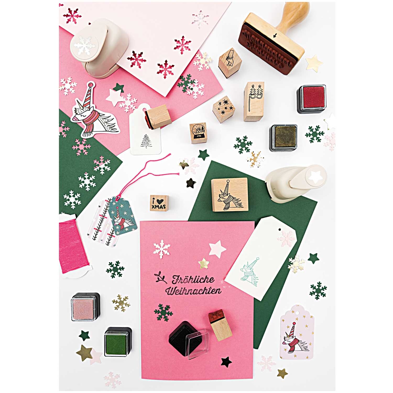 Paper Poetry Stanzer Stern 1,6cm von Rico Design auf einem Tisch mit weihnachtlichen Bastelmaterialien, Stempeln und buntem Papier.