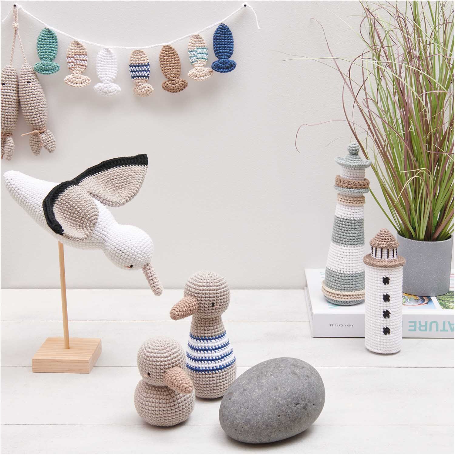 Creative Ricorumi dk: Dekorative Häkeltiere und Leuchttürme in neutralen Tönen auf einem Tisch.