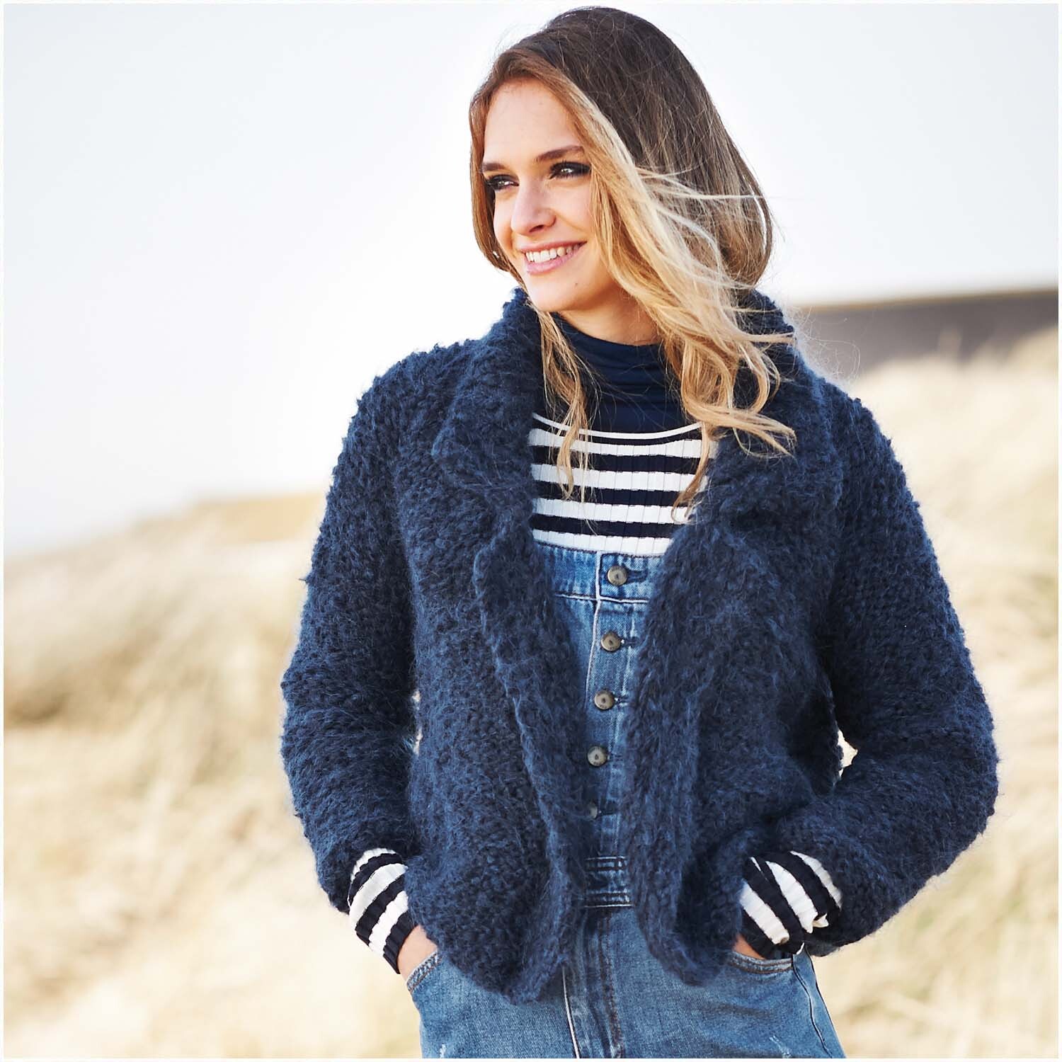 Fashion Fine Fur Super Chunky: Frau in blauer Strickjacke aus Rico Design Wolle, lächelt im Freien.