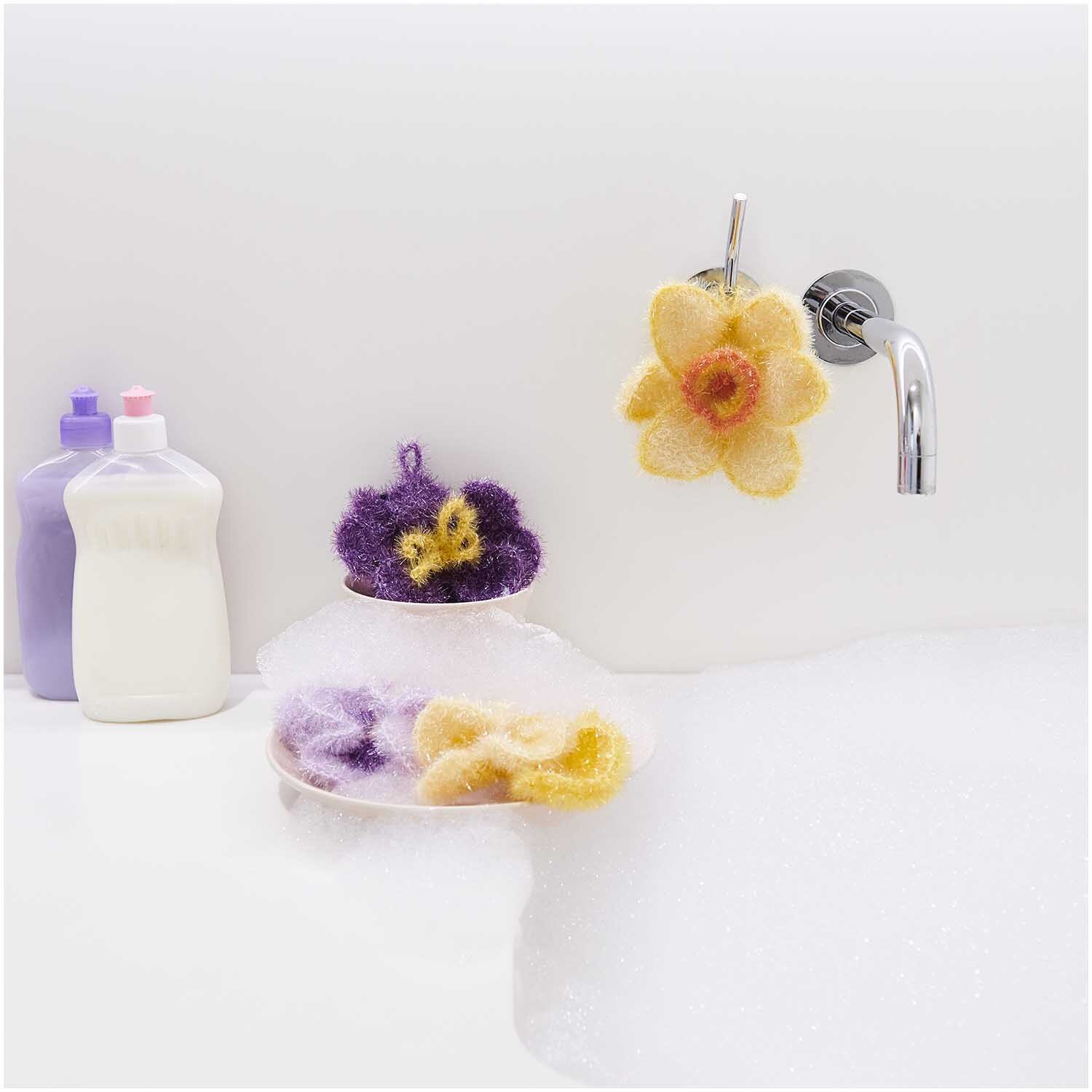 Häkelset Creative Bubble Frühlingsblume: Bunte Schwämme in Blütenform neben Seifenspendern am Waschbecken.