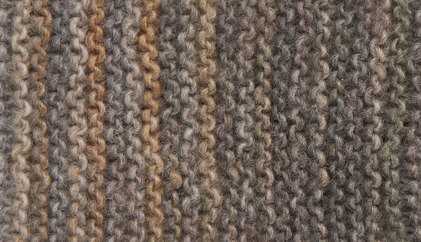 Strickanleitung Stirnband aus Creative Melange aran Wonderball. Nahaufnahme von gestricktem Stoff in Erdtönen.