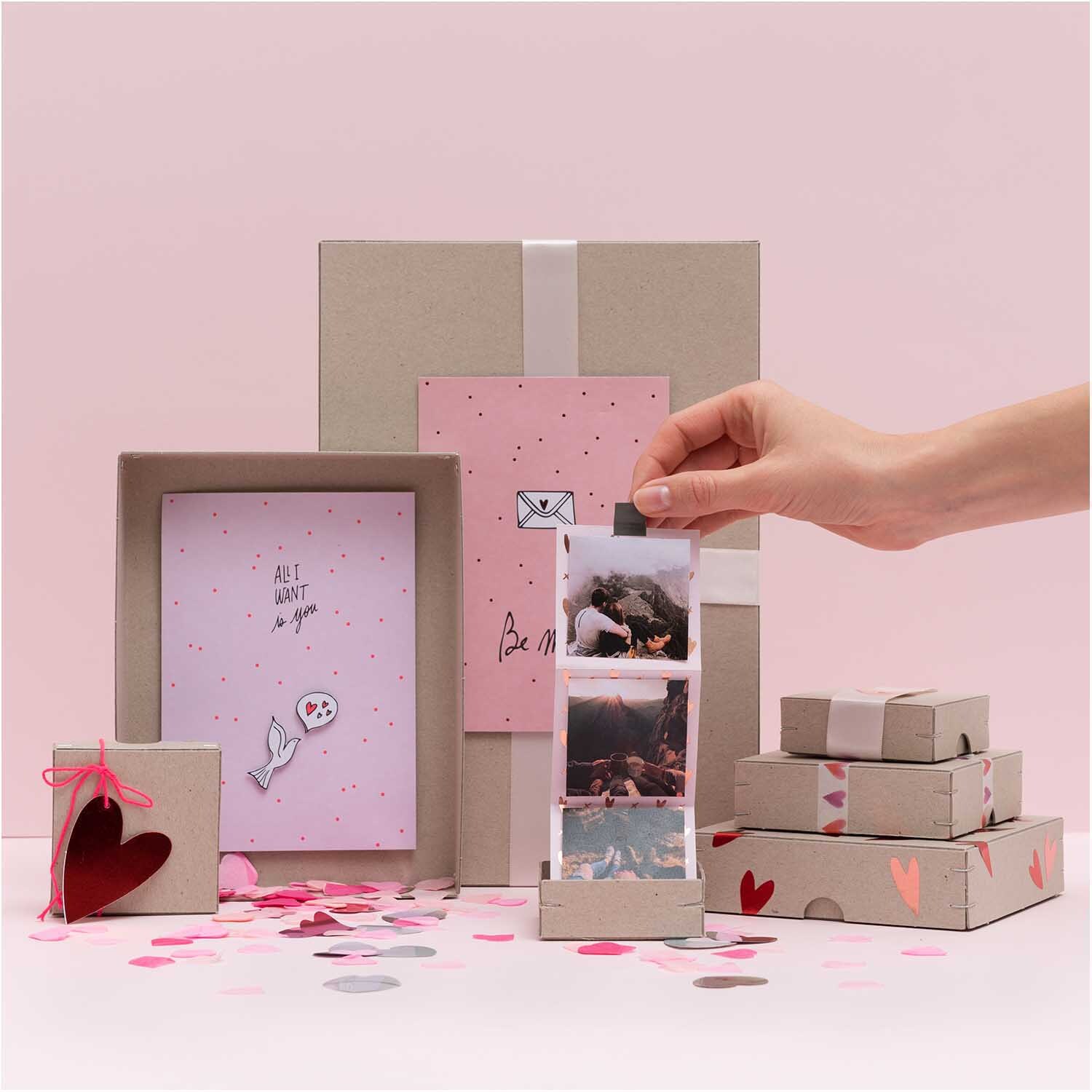 Konfetti Mix Herz 20g von Rico Design: Hand arrangiert Fotos und Geschenke auf rosa und grauem Hintergrund.