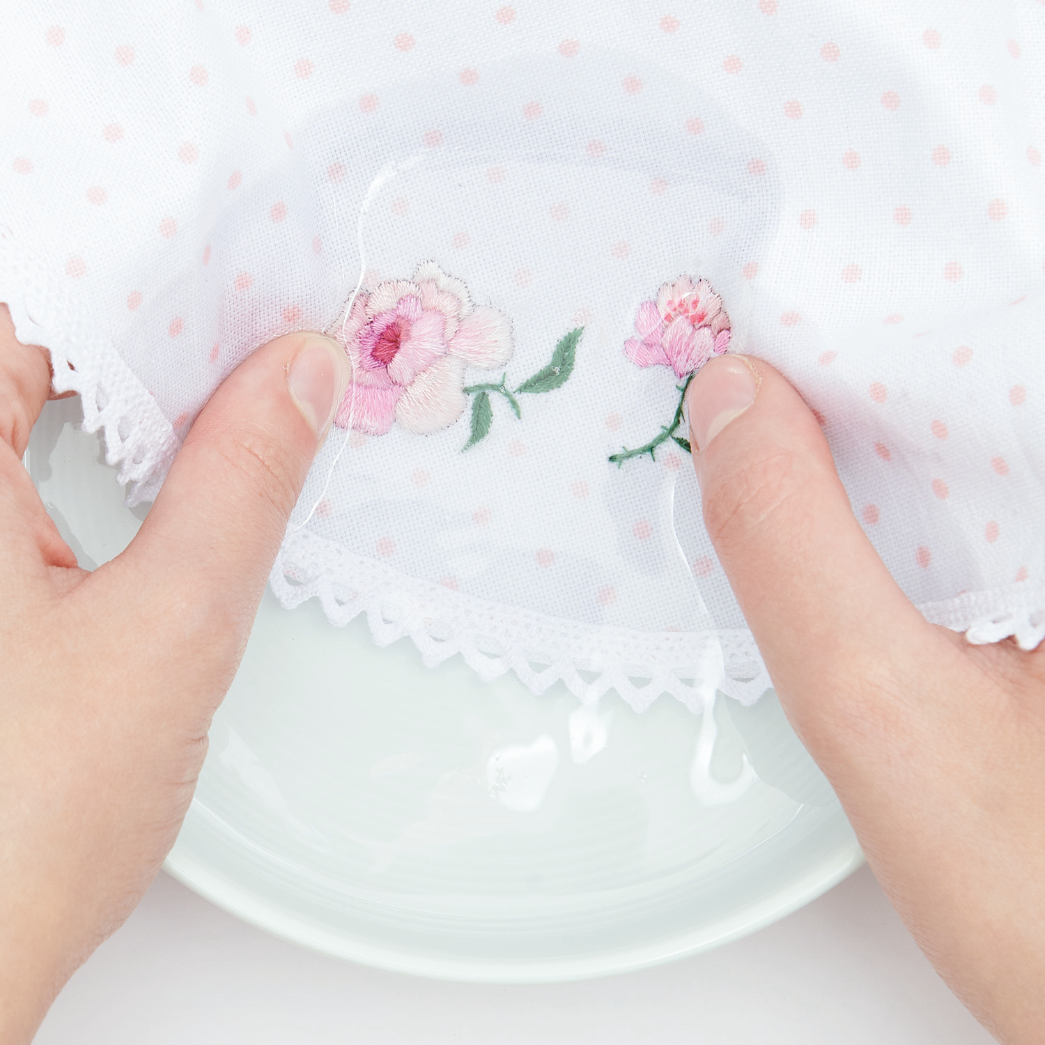Stick and Stitch Rosen: Hände halten ein weißes Tuch mit gestickten Rosen von Rico Design über einem Teller.