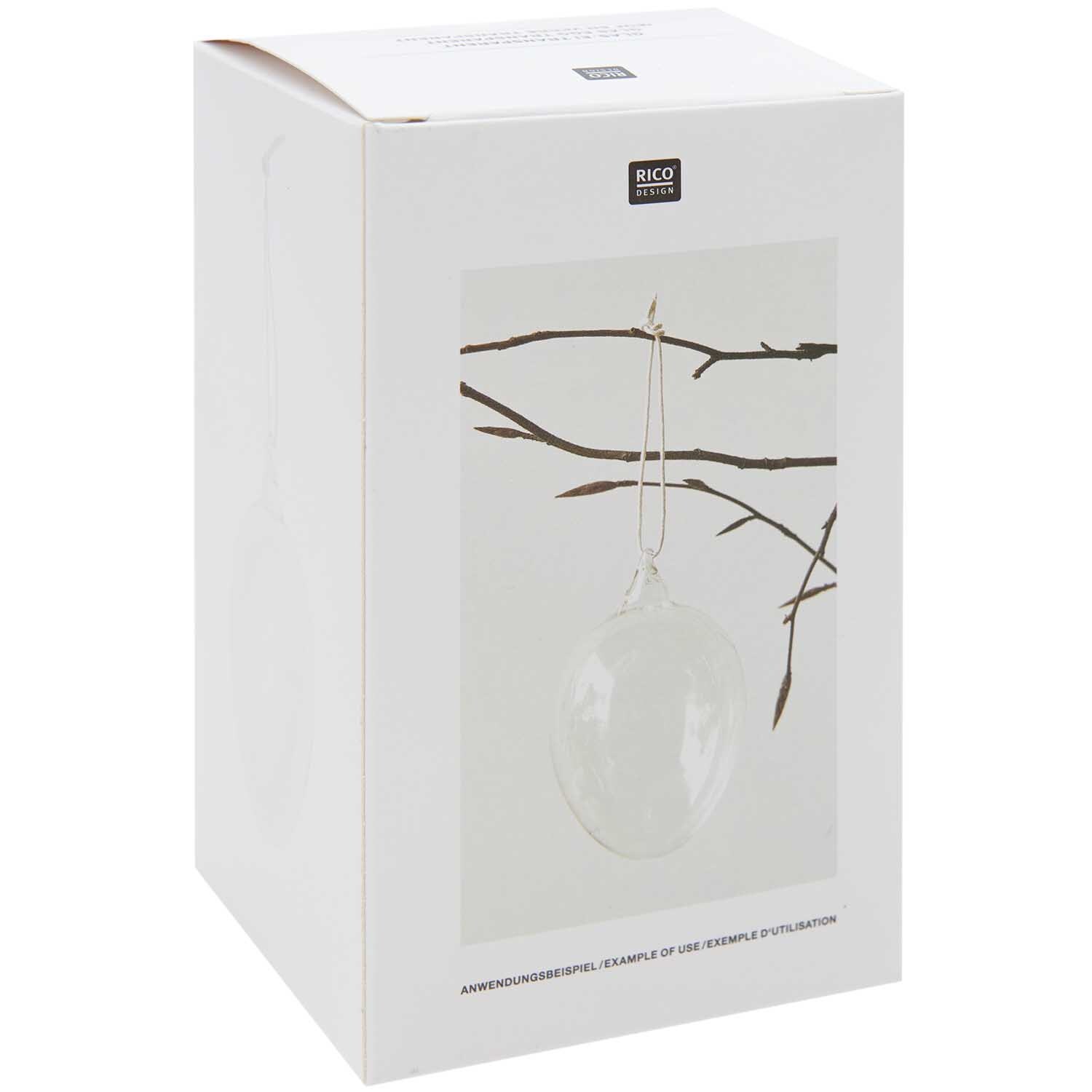 Glas Ei transparent Ø 7cm von Rico Design, hängend an einem Ast, in einer schlichten Verpackung.