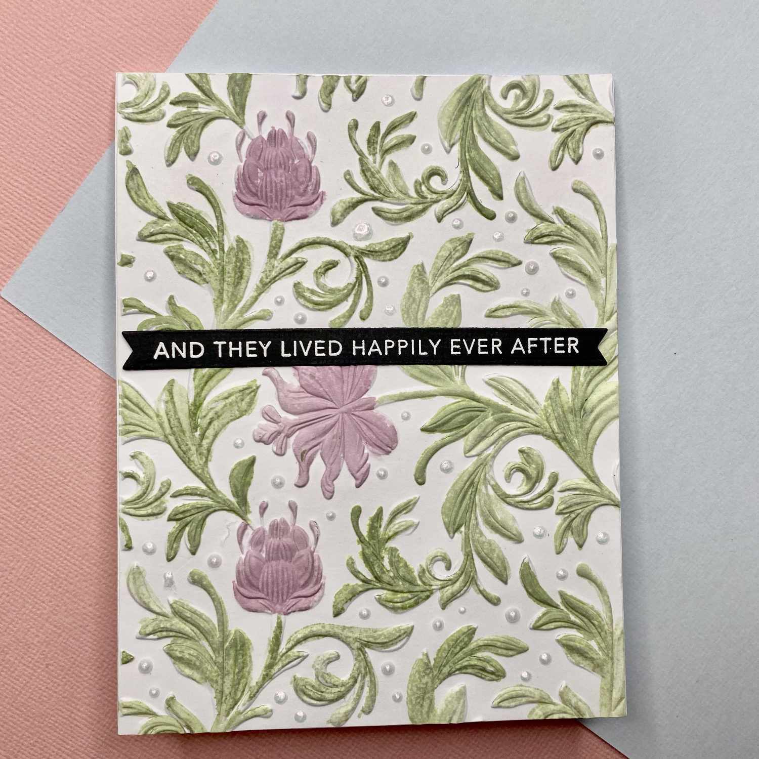 3D Textured Fades Embossing Folder Botanical mit floralen Mustern in Rosa und Grün auf einer Karte.