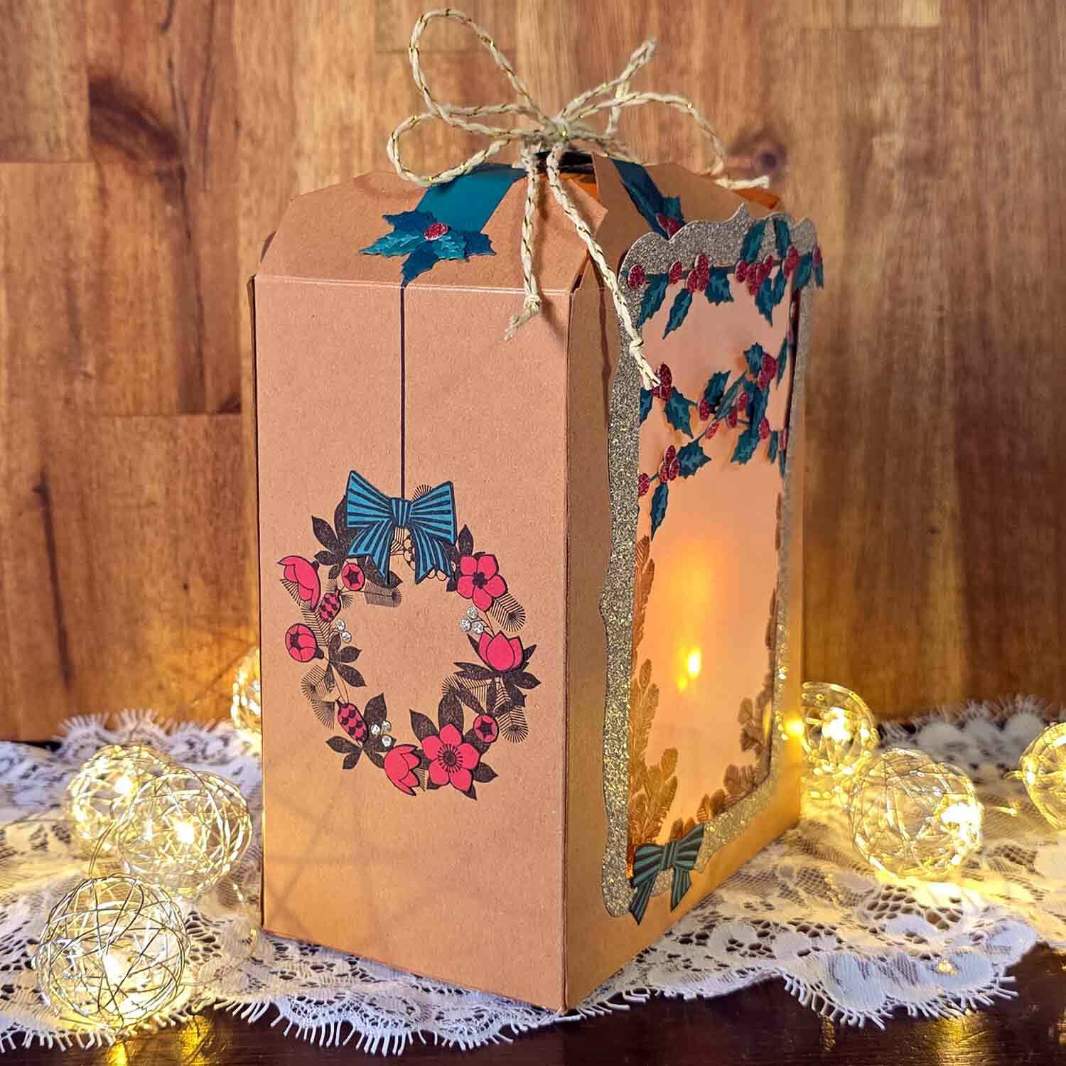Eine Weihnachtslaterne mit ausgestanzten Papierkränzen und Ilex-Blättern verziert.