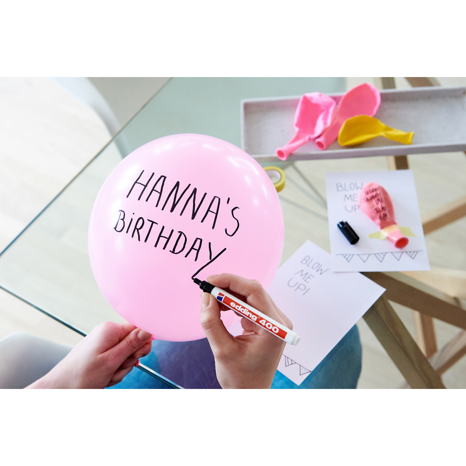 400 Permanentmarker schwarz 1mm schreibt auf rosa Ballon. edding Stift liegt auf Tisch mit Karten und Luftballons.