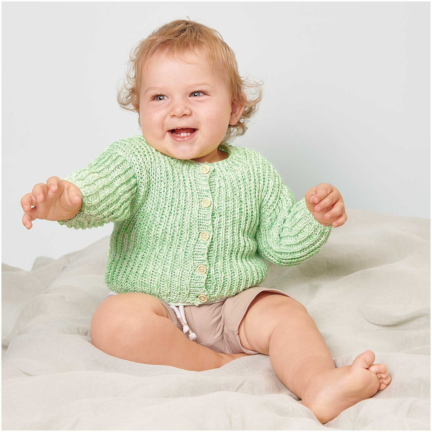 Creative Make It Neon: Ein lächelndes Baby trägt einen gestrickten, grünen Pullover von Rico Design.