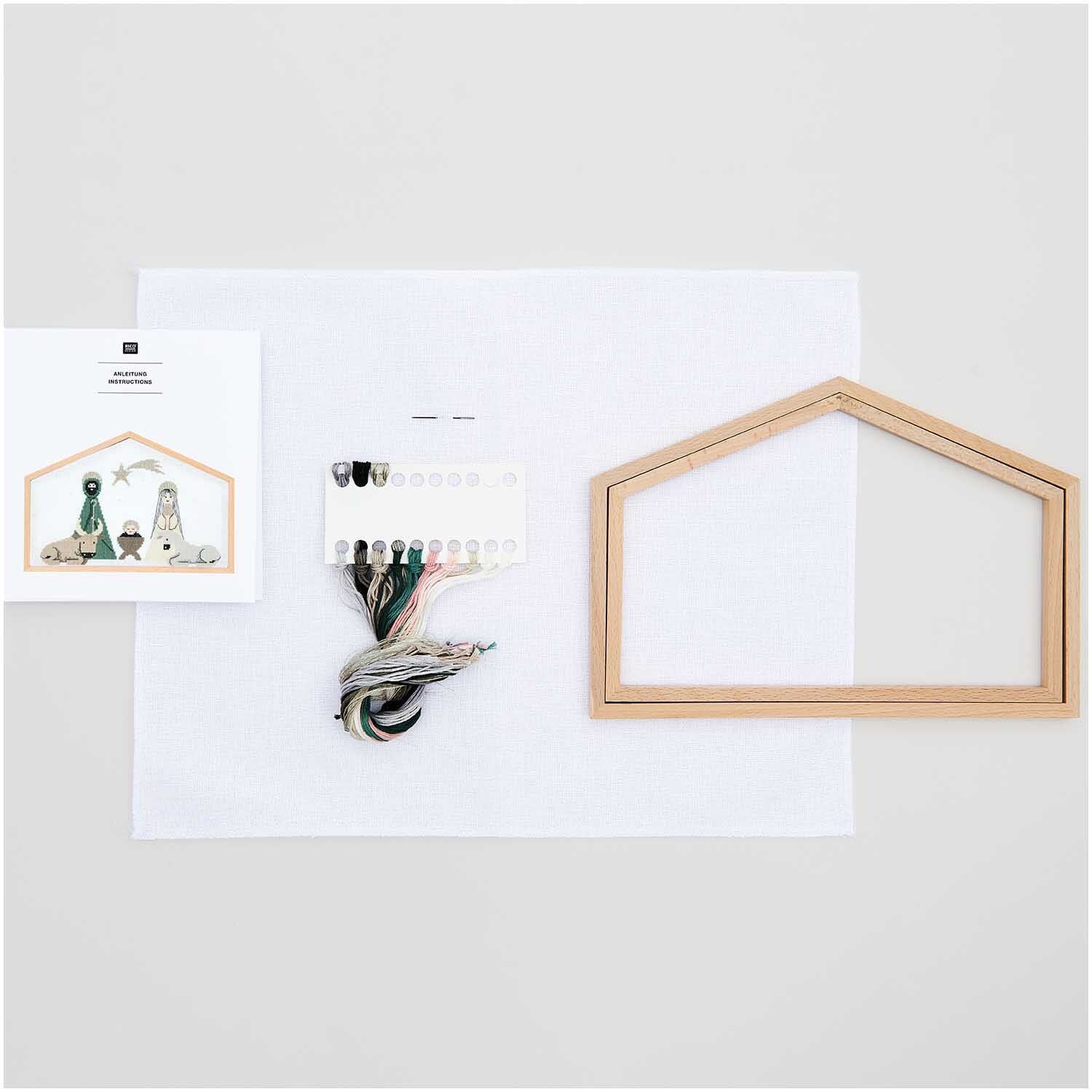 Stickpackung Krippe groß 28x19cm mit Holzrahmen, Garn und Anleitung von Rico Design auf weißem Hintergrund.