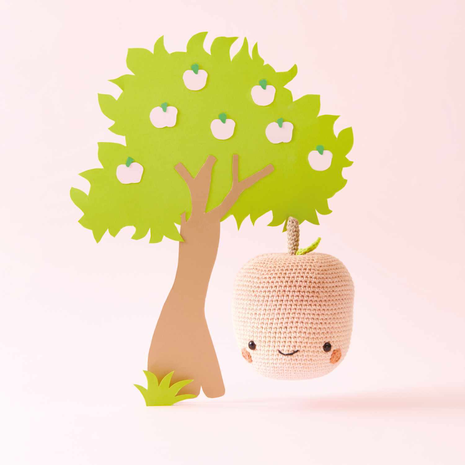 Häkelset Apfel aus Ricorumi Fresh Friends: Ein gehäkelter Apfel neben einem grünen Papierbaum mit weißen Äpfeln.