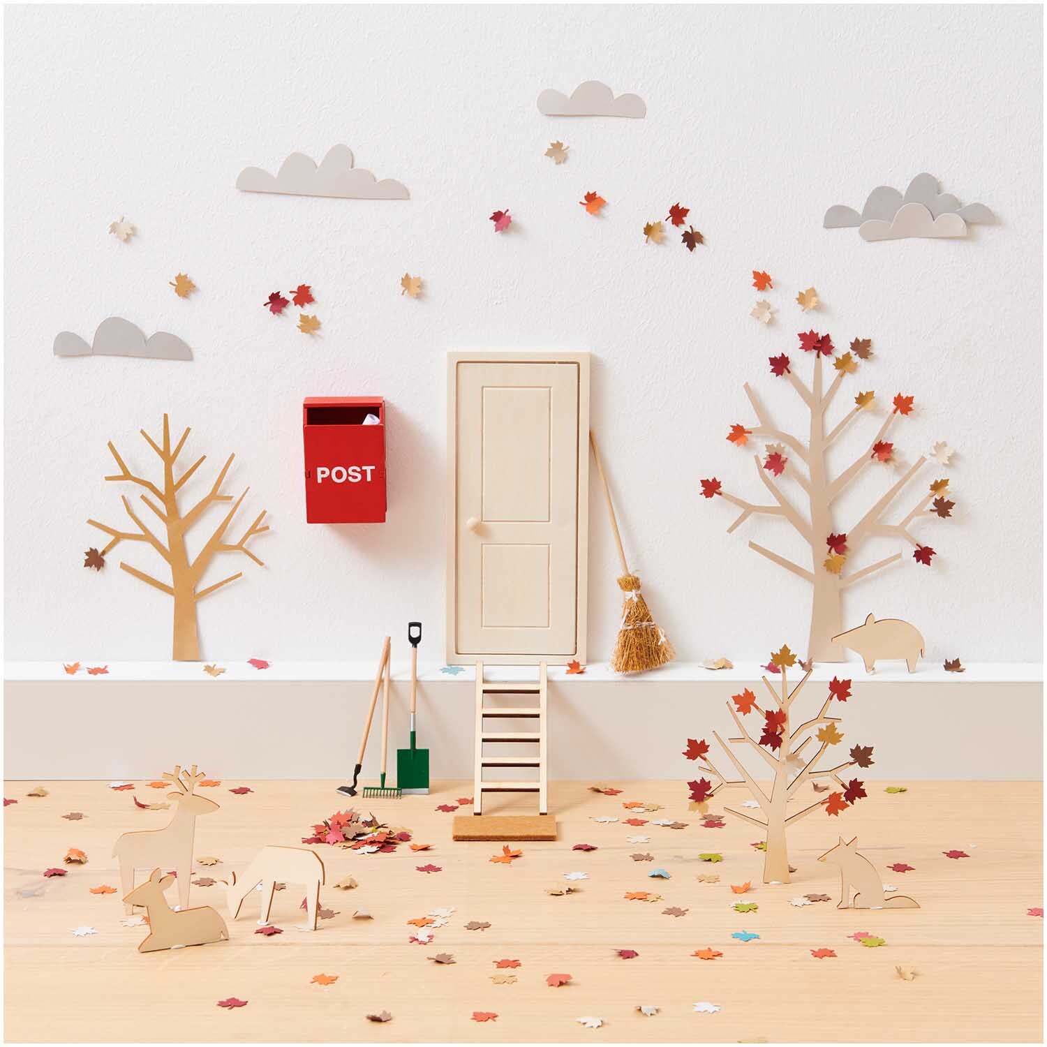 Miniatur Leiter 5x12cm vor einer dekorativen Szene mit Bäumen, Tür und rotem Briefkasten.