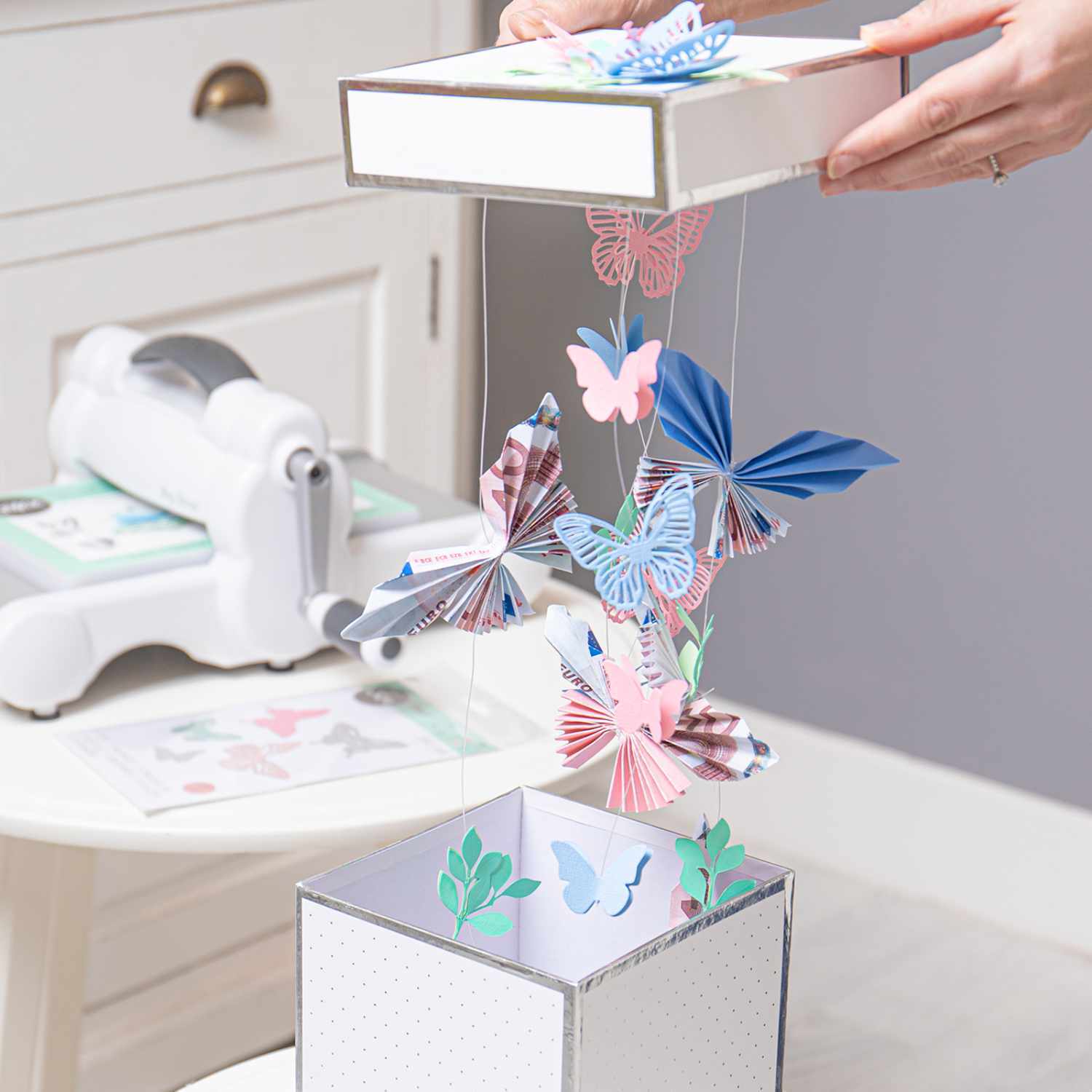 Bastelanleitung Geldgeschenk mit Schmetterlingen: Bunte Papier-Schmetterlinge schweben aus einer dekorativen Box.