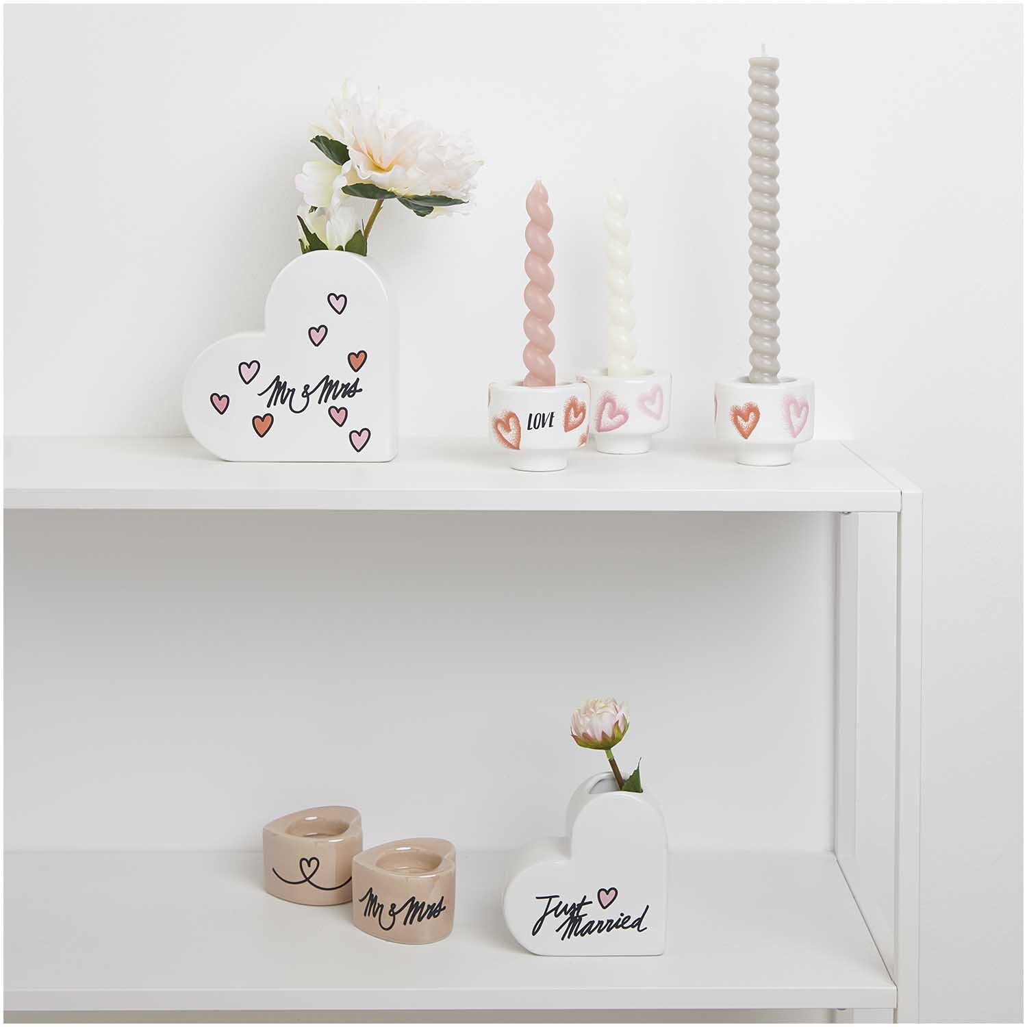 Transfermotiv Just Married 10 Stück: Dekorative Kerzenhalter und Vasen mit Herzmotiven auf einem Regal.